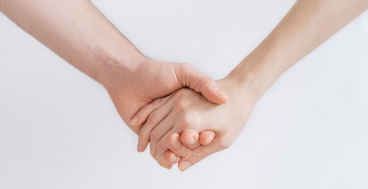 fotografia delle mani di due persone che si tengono per mano